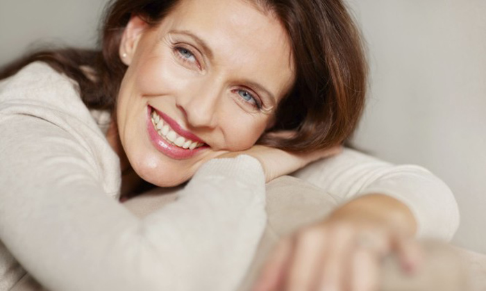 Pretty smiling middle aged brunette relaxing on a couch