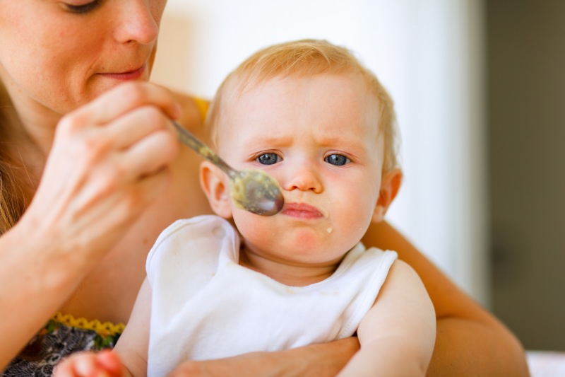 Young mother feeding adorable baby