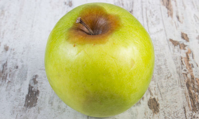 bigstock-Spoiled-Apple-On-Old-Wooden-Wh-111303320