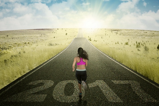 Picture of female athlete running toward sunrise with numbers 2017 on the road